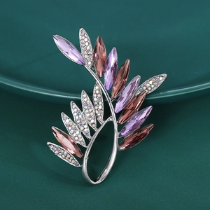 Detailed view of elegant leaf brooch with purple crystal and sparkling rhinestones
