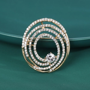 Vue rapprochée d'une broche spirale dorée avec strass brillants sur fond vert foncé