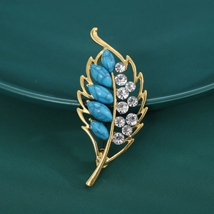 Close-up of gold hollow leaf brooch with turquoise stones and sparkling rhinestones