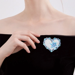 Elegant heart-shaped brooch with blue flowers and pearls on black dress