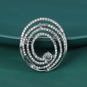 Gros plan d'une broche spirale argentée avec strass brillants sur fond vert sombre