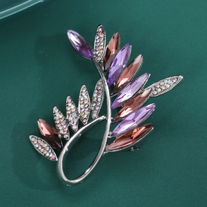 Detail of vintage leaf brooch with purple crystals and sparkling rhinestones on green