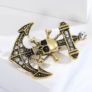 Close-up of golden anchor brooch with skull and crossbones featuring sparkling rhinestones