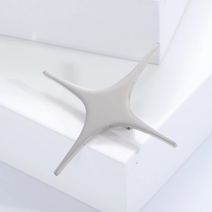 Minimalist silver four-pointed star brooch made of polished alloy on a white geometric base