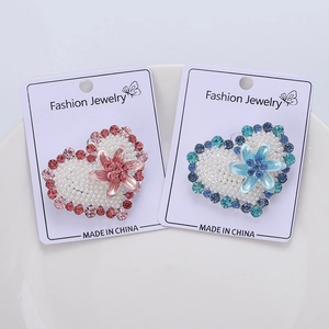Detailed macro view of heart-shaped pearl brooches with colorful rhinestones on a white card