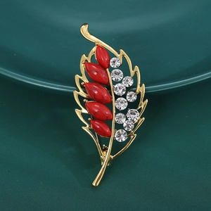 Detailed close-up of golden leaf brooch with red stones and white rhinestones