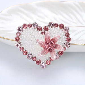 Macro shot of an elegant heart brooch featuring pink rhinestones and white pearls
