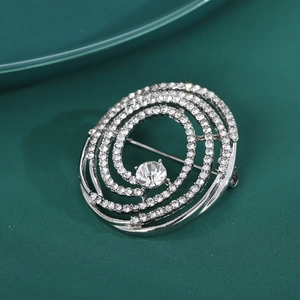 Élégante broche spirale argentée avec strass et cristal sur tissu vert foncé