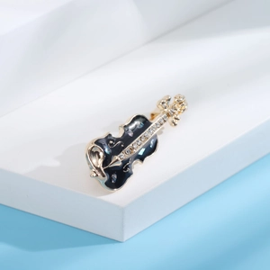 Détail macro d'une broche violon avec émail noir, strass brillants et finition dorée