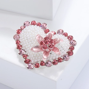 Close-up of heart-shaped brooch with pink flower, pearls and sparkling rhinestones