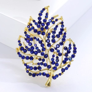 Fashionable golden leaf brooch with dark blue crystals on a clean minimalist white background