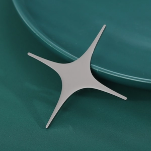 Close-up of a silver-polished four-pointed star brooch on a dark green textured background