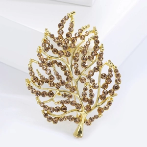 Detailed macro view of gold-plated leaf brooch with sparkling champagne rhinestones