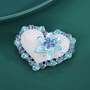 Detailed macro of heart brooch with blue crystals, pearls and 3D flower center
