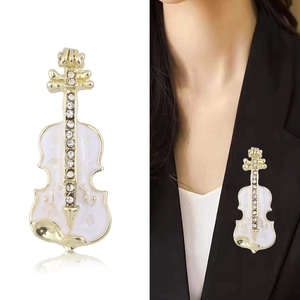 Broche violon dorée élégante avec nacre et strass sur un costume noir classique