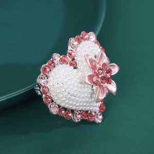 Detailed macro shot of heart-shaped pearl brooch with pink rhinestones and 3D floral accent