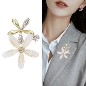 Elegante Blumenbrosche mit Strasssteinen und Perlenblättern auf einem grauen Blazer