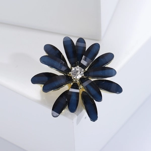 Macro view of blue daisy flower brooch with central zircon and golden metallic base