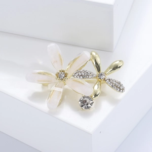 Makro-Detail einer eleganten Doppelblüten-Brosche mit weißen Blüten und Kristallen