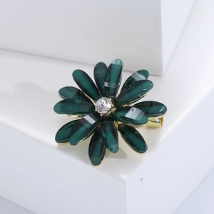 Macro detail of dark green resin flower brooch with a central sparkling rhinestone