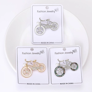 Detailed close-up of bicycle brooches with pearls and rhinestones on card packaging