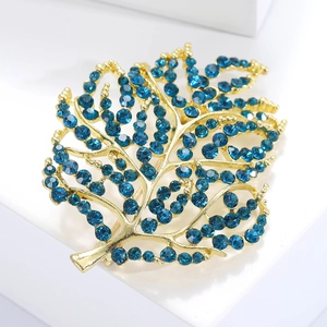Detail of leaf-shaped brooch with blue crystals and gold-tone intricate metalwork