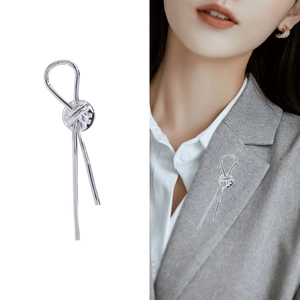 Minimalist silver knot brooch for women on white background and worn on a grey blazer