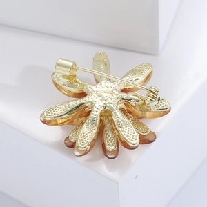 Detail view of the golden metal brooch back with safety clasp and resin flower petals