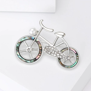 Detail of a silver bicycle brooch featuring sparkling rhinestones and iridescent shell wheels