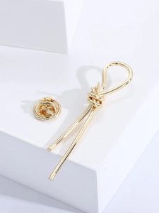 Detailed view of a golden minimalist knot brooch with a matching metal butterfly clasp