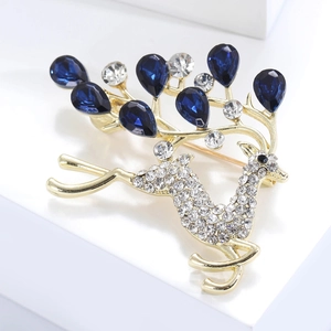 Broche cerf dorée exquise avec diamants blancs et cristaux bleu foncé sur un socle blanc