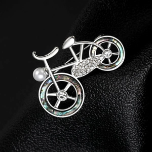 Macro detail of bicycle brooch featuring sparkling crystals and iridescent shell inlay