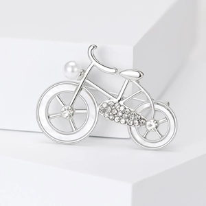 Detailed close-up of a silver bicycle brooch with pearls and sparkling rhinestones