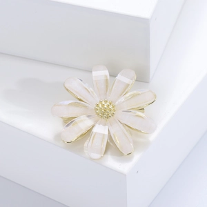Détail de la broche marguerite blanche avec bords dorés et pétales aux reflets nacrés