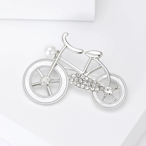 Silver bicycle brooch with sparkling crystals and a white pearl on a clean white background