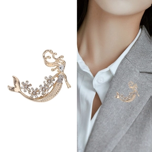 Elegante spilla a sirena con cristalli scintillanti e finitura dorata su blazer grigio