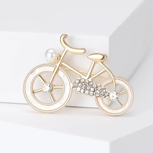 Detailed view of bicycle brooch with gold metal, white enamel wheels and sparkling rhinestones
