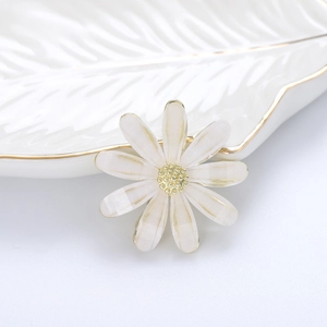 Gros plan d'une broche marguerite blanche avec cœur doré sur un plateau en céramique