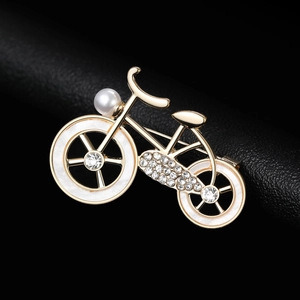 Detailed close-up of golden bicycle brooch featuring white pearls and sparkling rhinestones