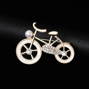 Detailed macro view of a gold bicycle brooch with inlaid pearls and sparkling crystals