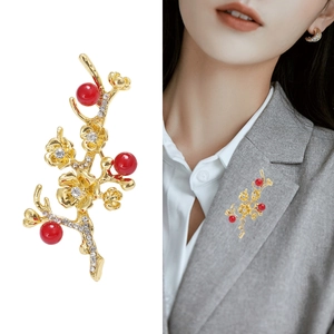 Detailed view of elegant gold plum blossom brooch with red pearls and crystals on a suit