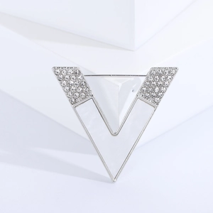 Detailed view of silver V-shaped brooch with sparkling rhinestones and white mother of pearl