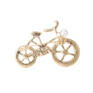 Elegant golden bicycle brooch with textured metal finish and a white pearl accent