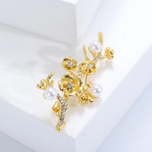 Detailed macro view of an elegant gold floral branch brooch with pearls and crystals