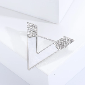 Minimalist silver V-shaped brooch with white shell inlay and sparkling rhinestones