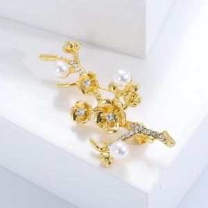 Elegant gold plum blossom brooch with white pearls and crystals on minimalist stand