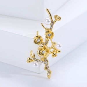 Detailed view of elegant gold flower branch brooch with pearls and rhinestones
