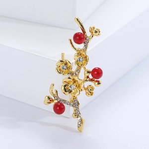 Macro detail of plum blossom brooch with red pearls and crystals on golden branch
