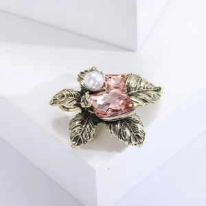 Detailed close-up of a vintage crystal flower brooch with pearl on a white background