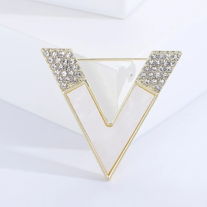 Detail of a golden V-shaped brooch with white enamel inlay and shimmering crystals